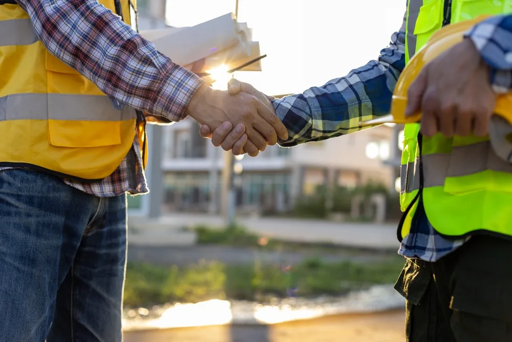 contractors shake hands at a construction site, liability concept