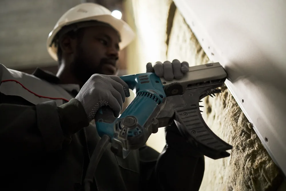 low angle of a construction worker using a nail gun
