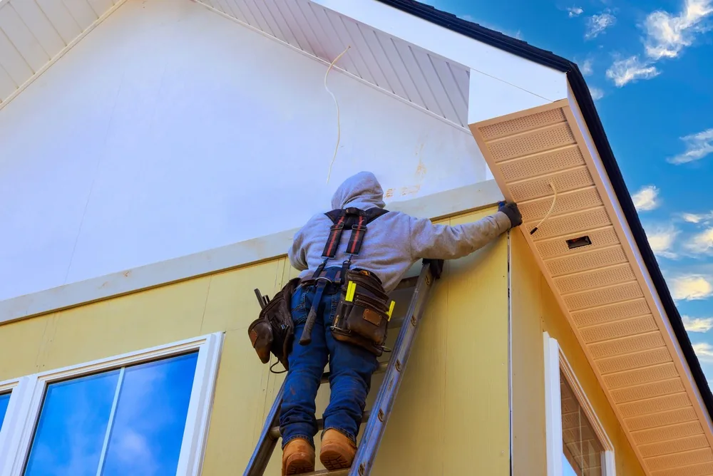worker climbs up a ladder to get to a roof