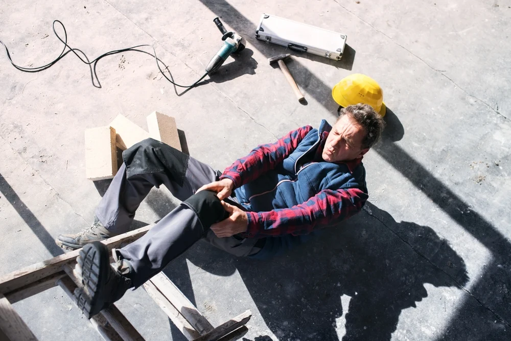 Construction worker holds his leg in pain after an injury.