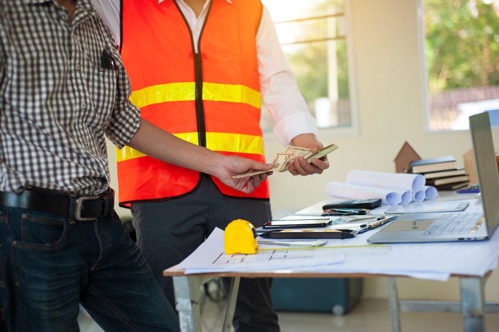 Trabajador de construcción recibe pagos en efectivo de su jefe.