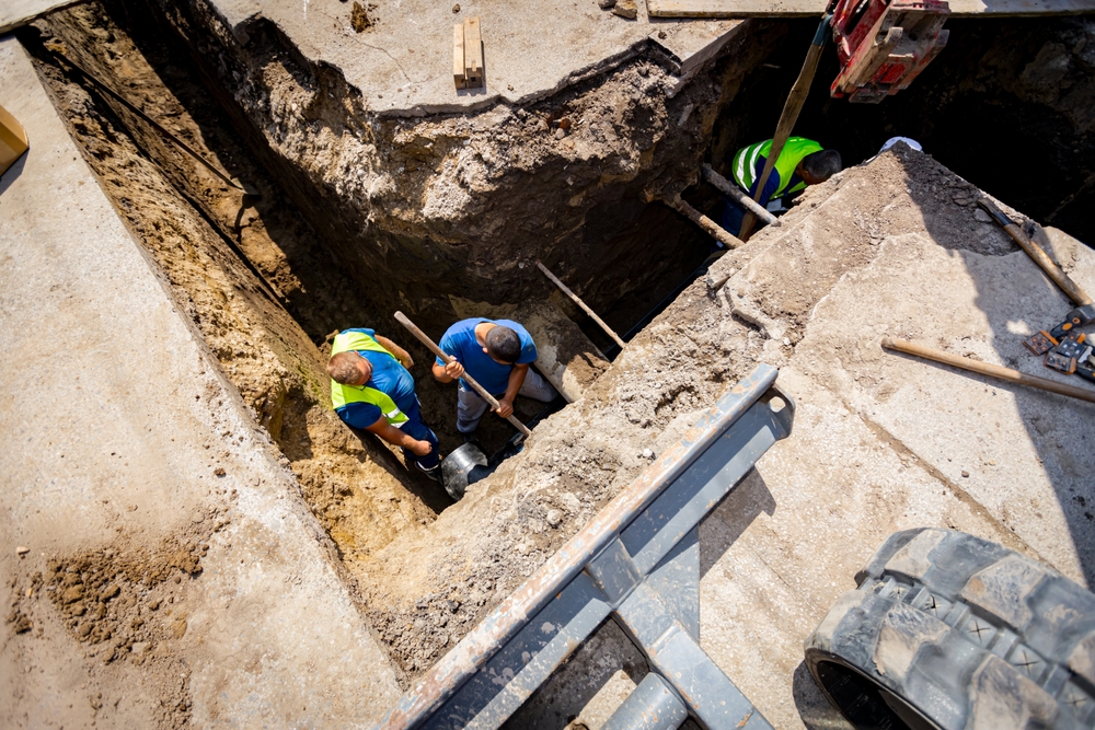 Construction workers work inside a trench.