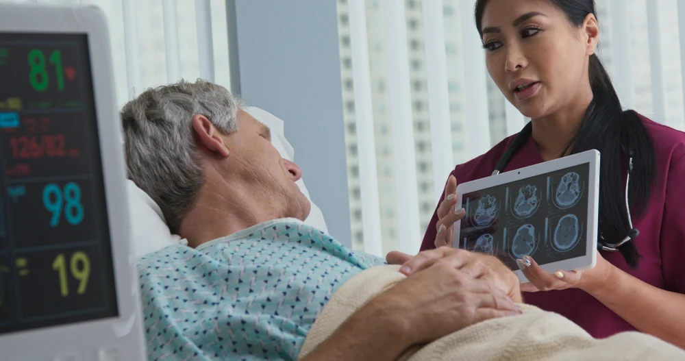 Doctor explains brain injury to patient in bed.