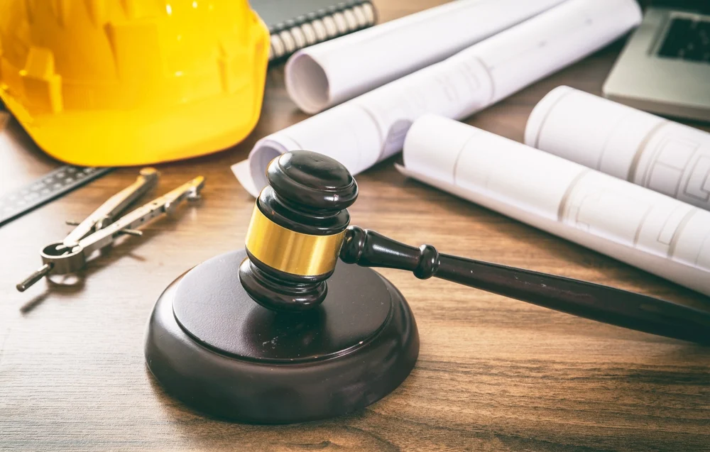 Judge's gavel on a table with construction equipment.