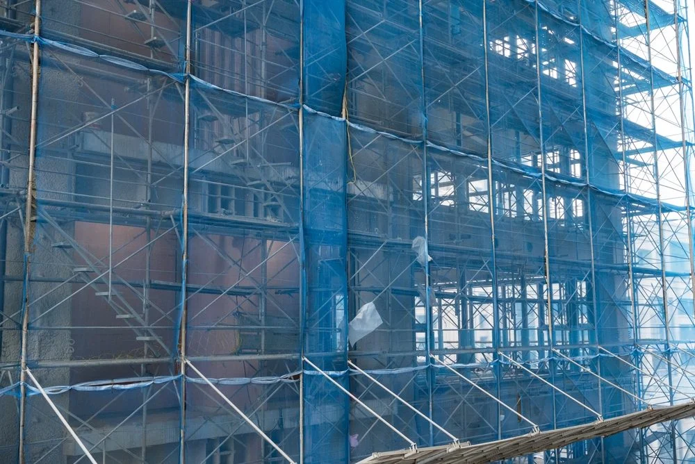 Andamio en un edificio en construcción envuelto en una red de seguridad azul.