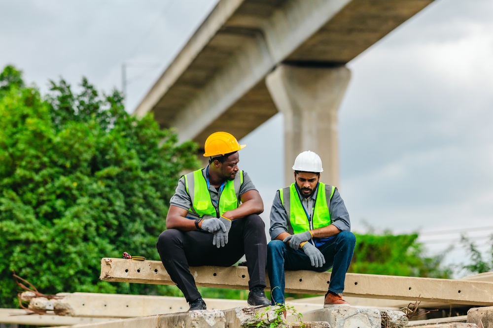 Two construction workers talk on a construction site.