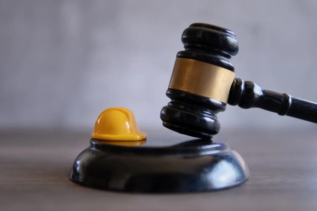 Cost of hiring a construction accident lawyer, construction hat and gravel.