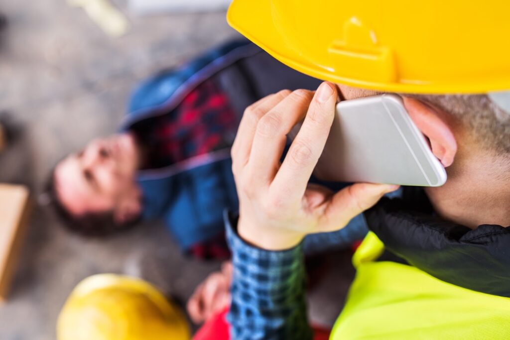 Construction worker calling ambulance after fall.