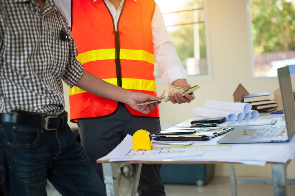 Construction worker receives cash from boss.