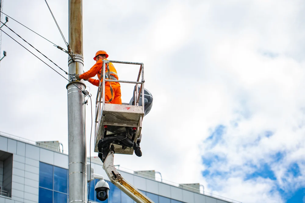 Electrician works on crane on height on a pole