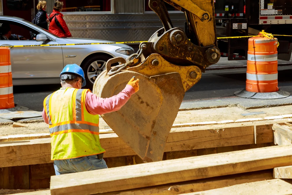 Construction worker guides an excavator at a New York City work site